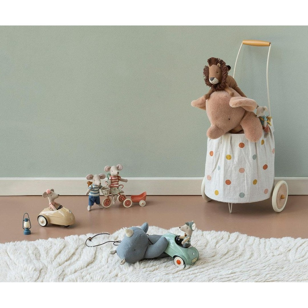 Maileg mice driving toy cars on a fluffy rug while a lion and elephant ride in a spotty trolley