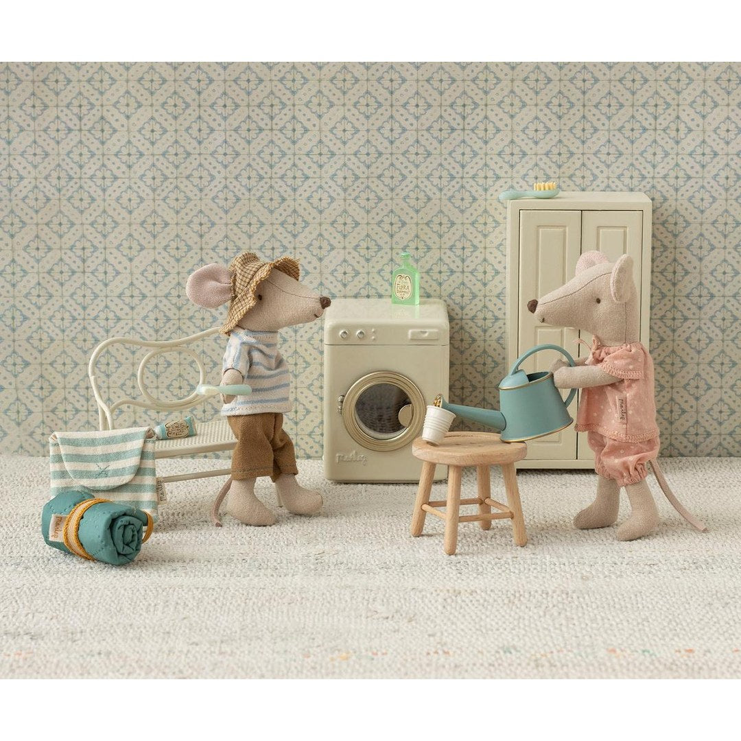 Maileg big sister mouse watering plants beside a washing machine while a mouse in a sun hat looks on
