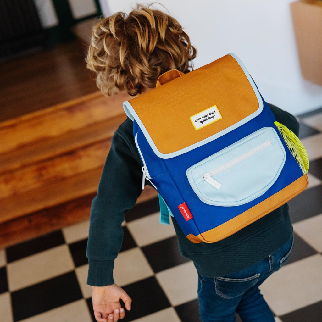 Child wearing a colorful backpack on a checkered floor