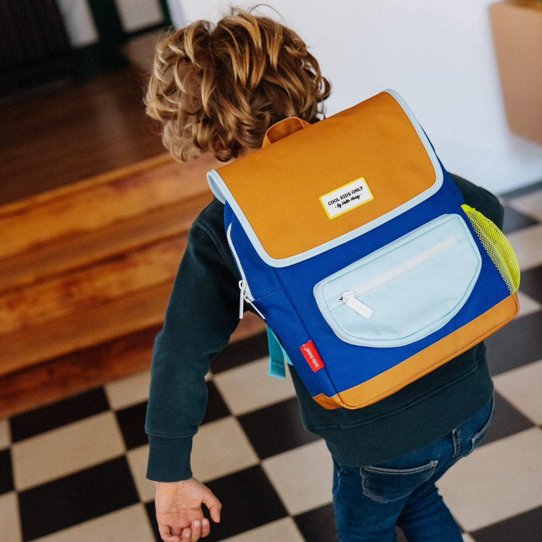 Child wearing a colorful backpack on a checkered floor