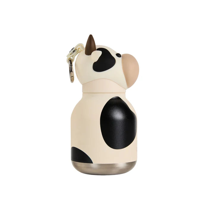 A cow-shaped insulated water bottle with a cream body, black spots, a brown horn, and a beige snout, shown on a plain white background.
