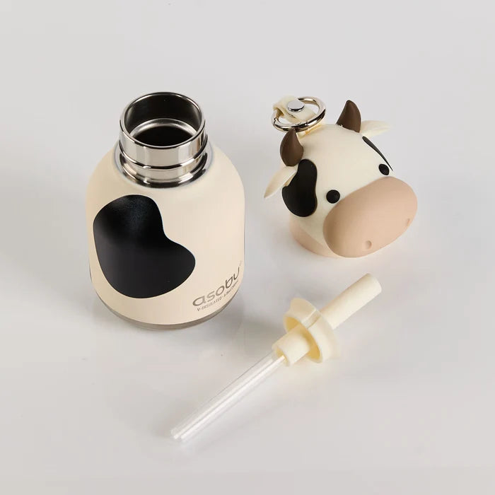 Cow-shaped bottle and keychain on a light gray background