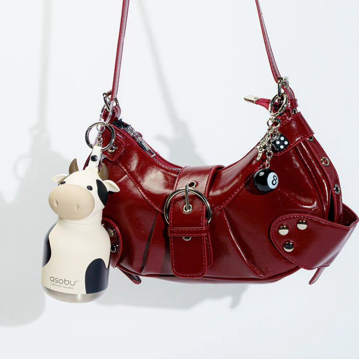 Red handbag with cow-shaped keychain on a white background