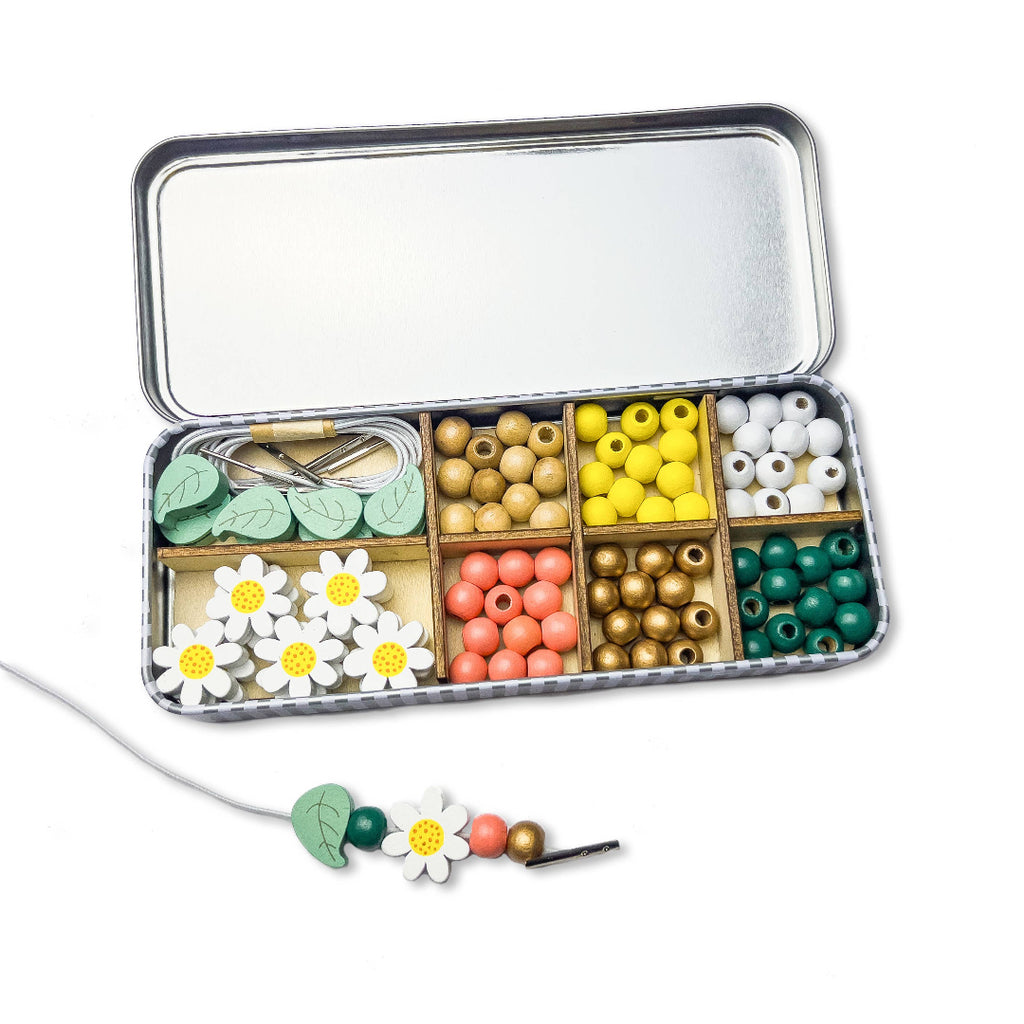 Colourful bead set in a tin with a sample necklace on a white background