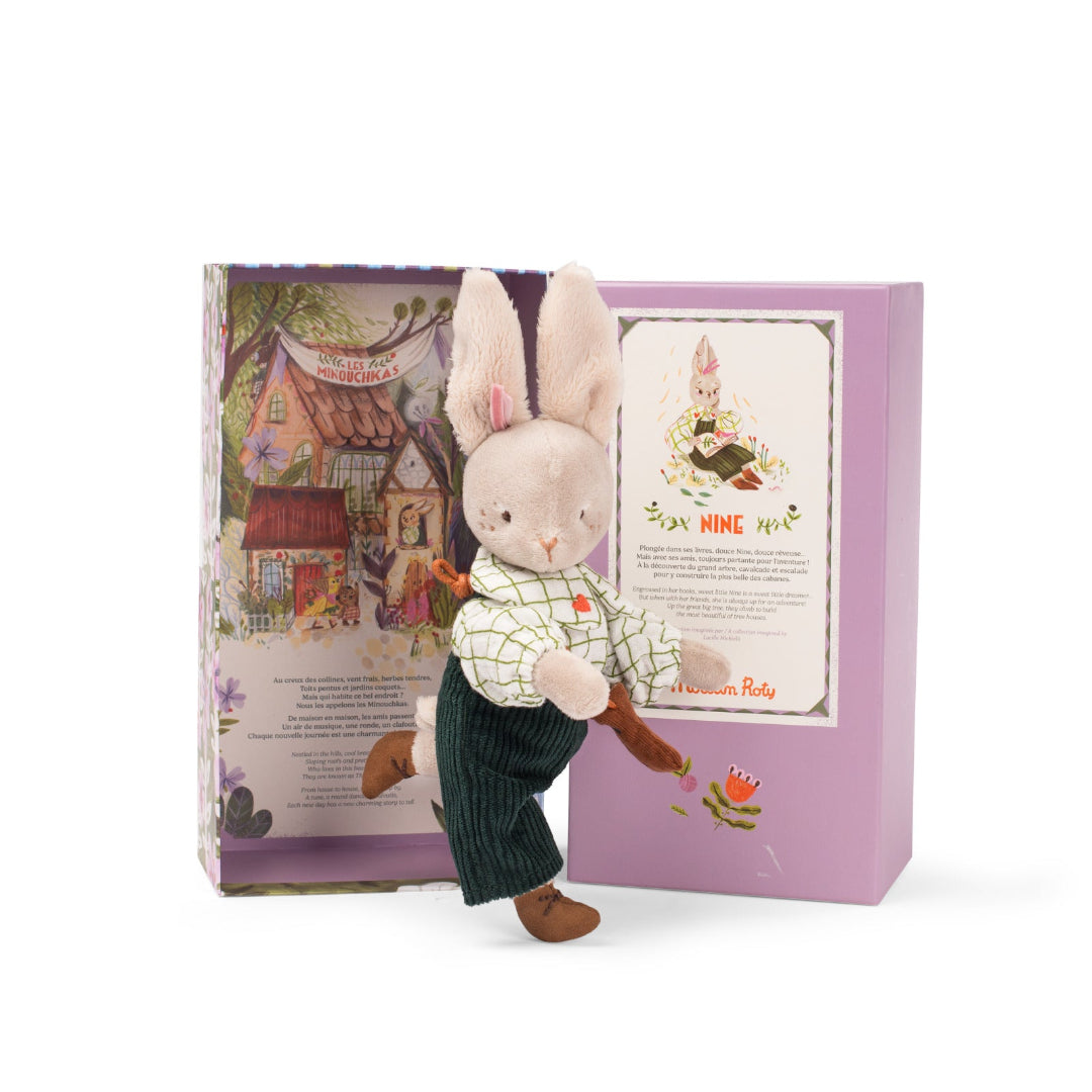 Stuffed rabbit toy with a checkered shirt and pants in front of a decorative box.