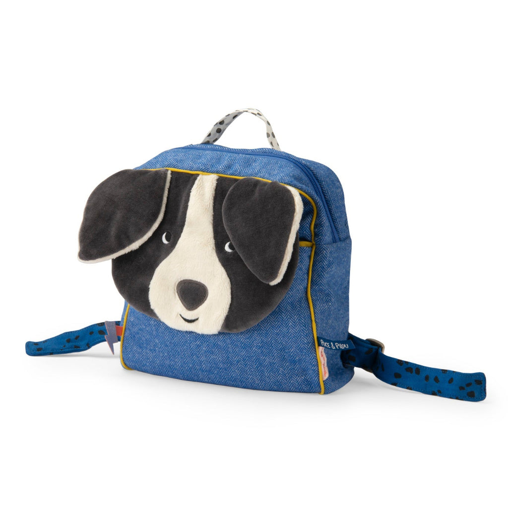 A small blue denim-style dog backpack with a plush dog face on the front, black-and-white ears, and matching blue patterned shoulder straps, photographed on a clean white background.