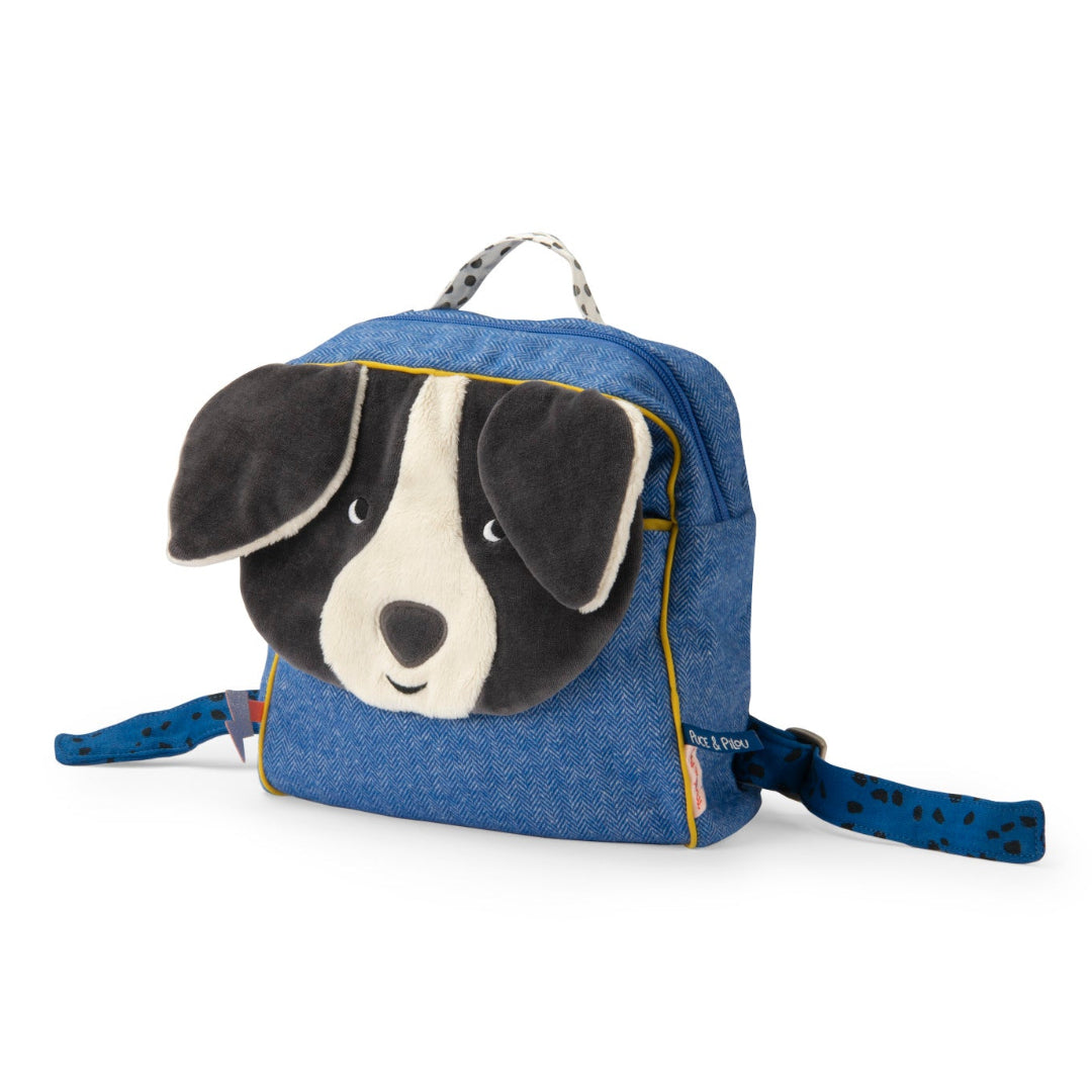 A small blue denim-style dog backpack with a plush dog face on the front, black-and-white ears, and matching blue patterned shoulder straps, photographed on a clean white background.