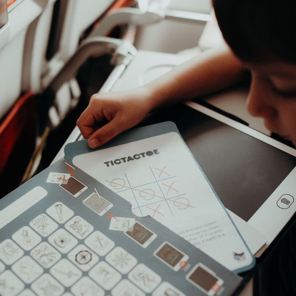Person using a tablet with a tic-tac-toe game on a table.