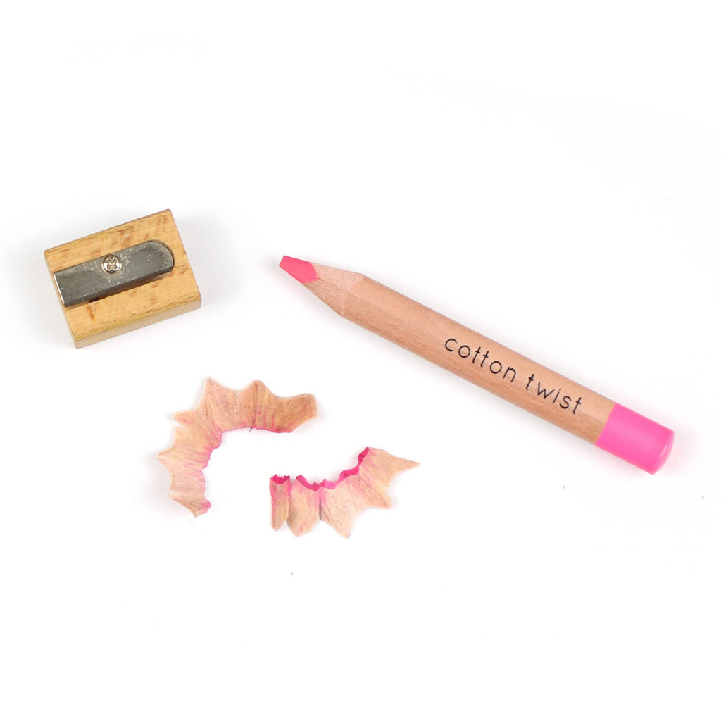 Pink pencil labeled 'cotton twist' with a wooden sharpener and two sharpened ends on a white background.