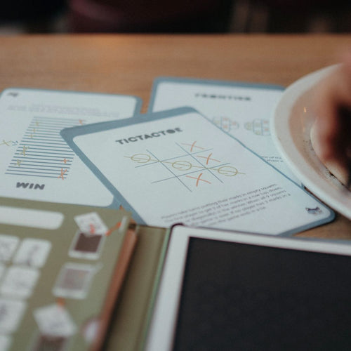 Close-up of a card game with 'Tic Tac Toe' cards on a wooden table.