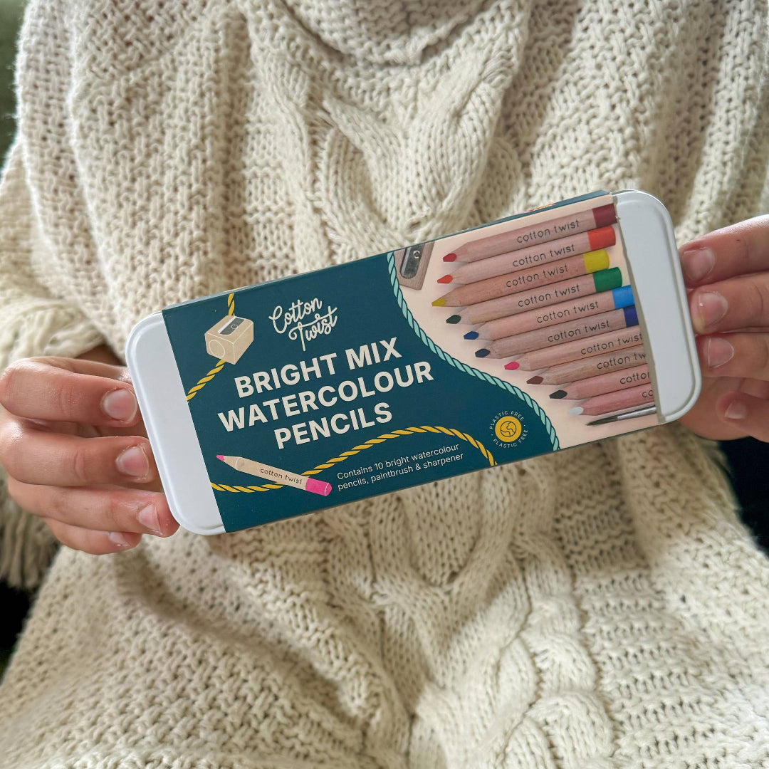Person holding a set of Cotton Twist Bright Mix Watercolour Pencils against a beige sweater background