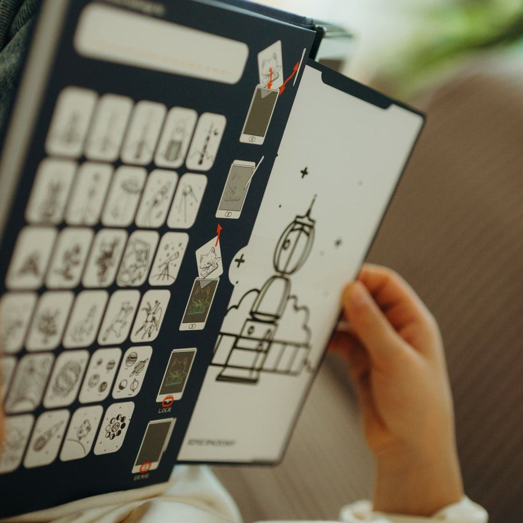 Child holding the navy Galaxy card holder, slipping a Soyuz rocket drawing card into the KIDYDRAW MINI