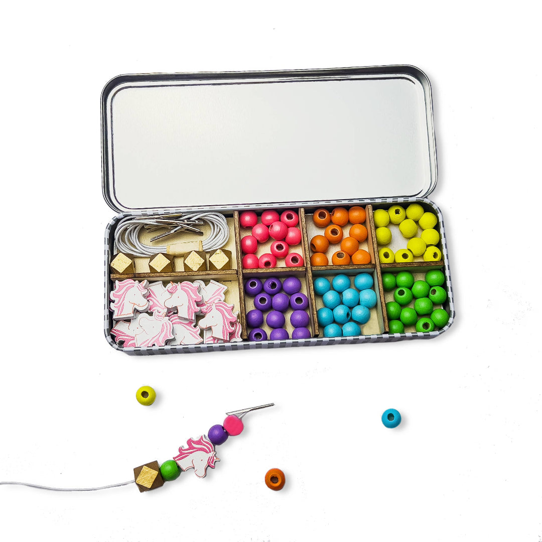 Colourful bead set with tools in a tin box on a white background