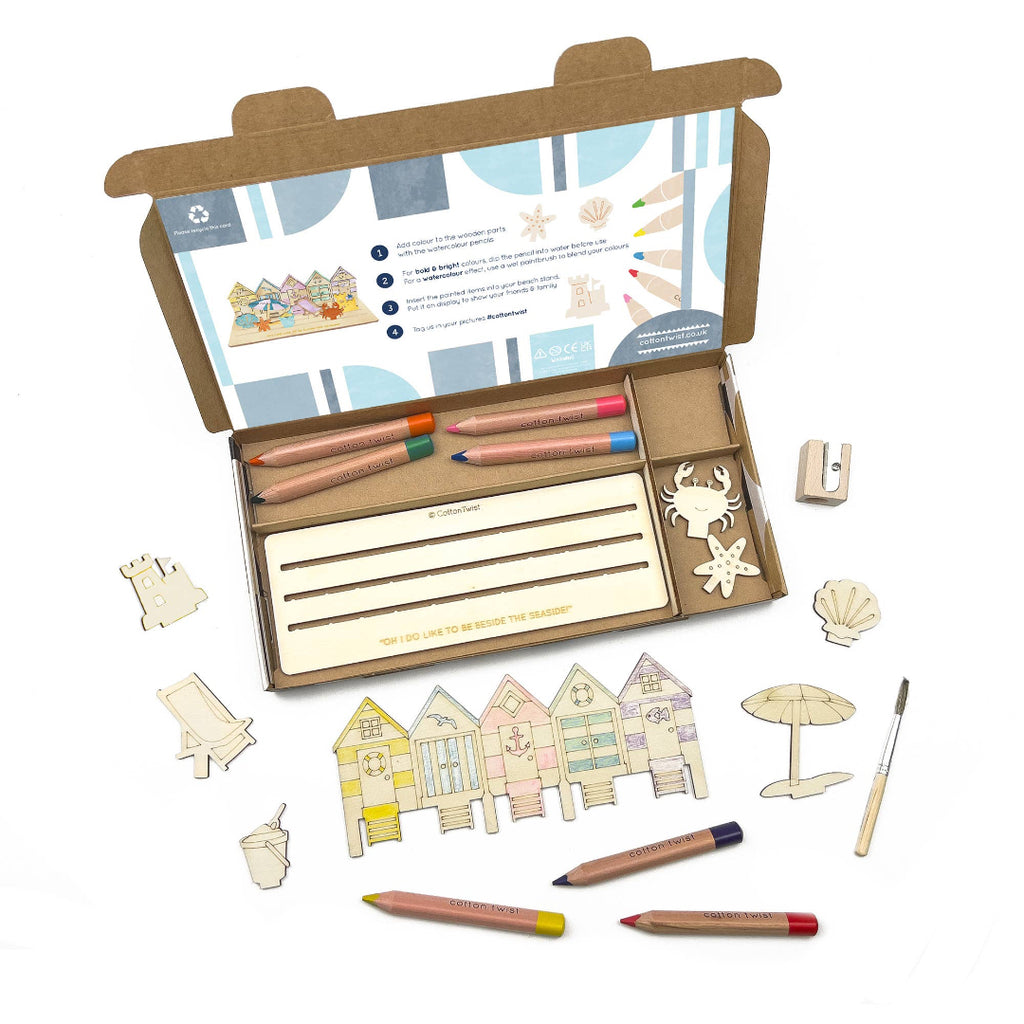 Coloring set with pencils, paper, and wooden beach-themed figures on a white background