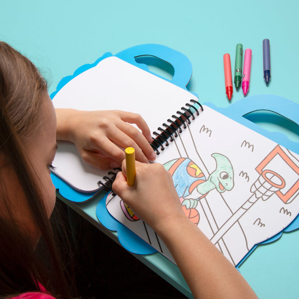 Child coloring a picture of a turtle with markers on a blue table.