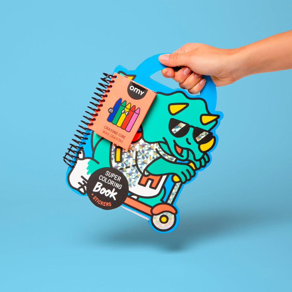 Hand holding a colorful children's activity book with stickers on a blue background