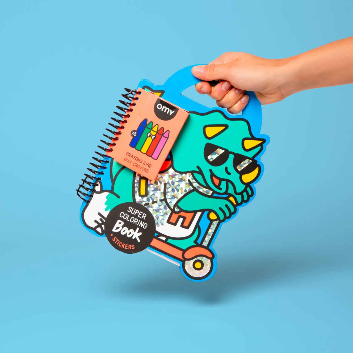 Hand holding a colorful children's activity book with stickers on a blue background