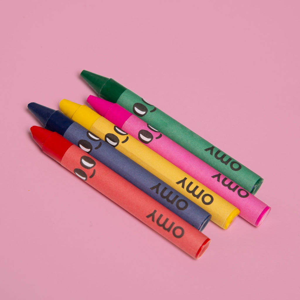 Colorful crayons with 'OMY' text on a pink background
