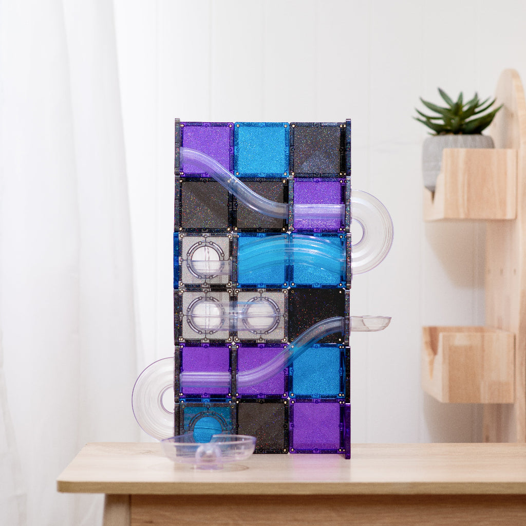 CONNETIX Ball Run Galaxy tower with clear tubes and purple, blue and black glitter tiles on a wooden table