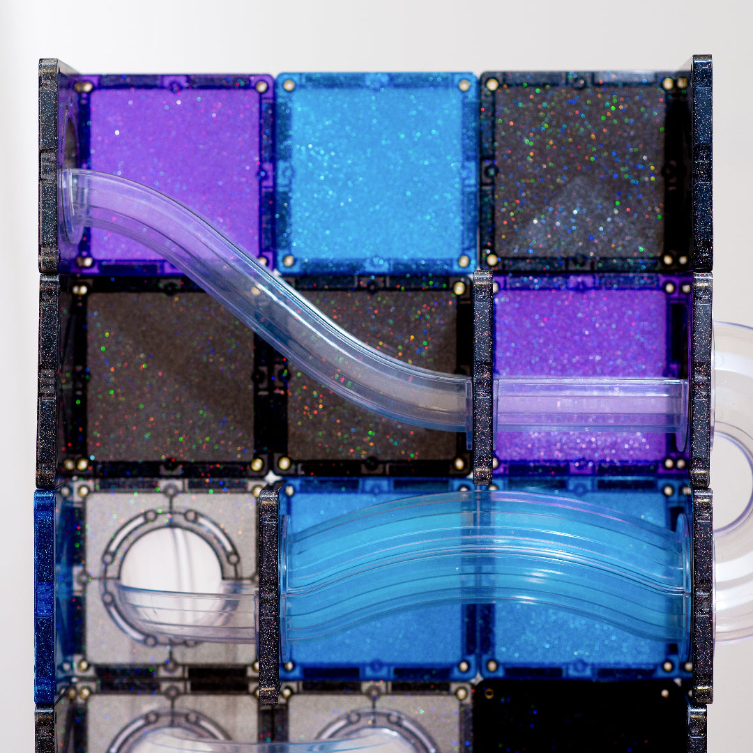 Close-up of CONNETIX Galaxy glitter tiles in purple, blue, black and silver with clear curved ball run tubes