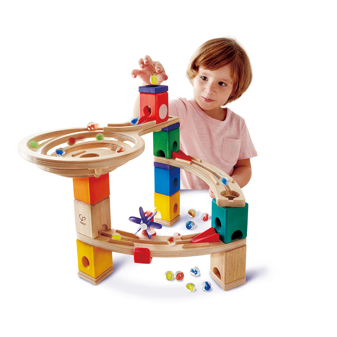 Child playing with a colorful wooden marble run toy set on a white background