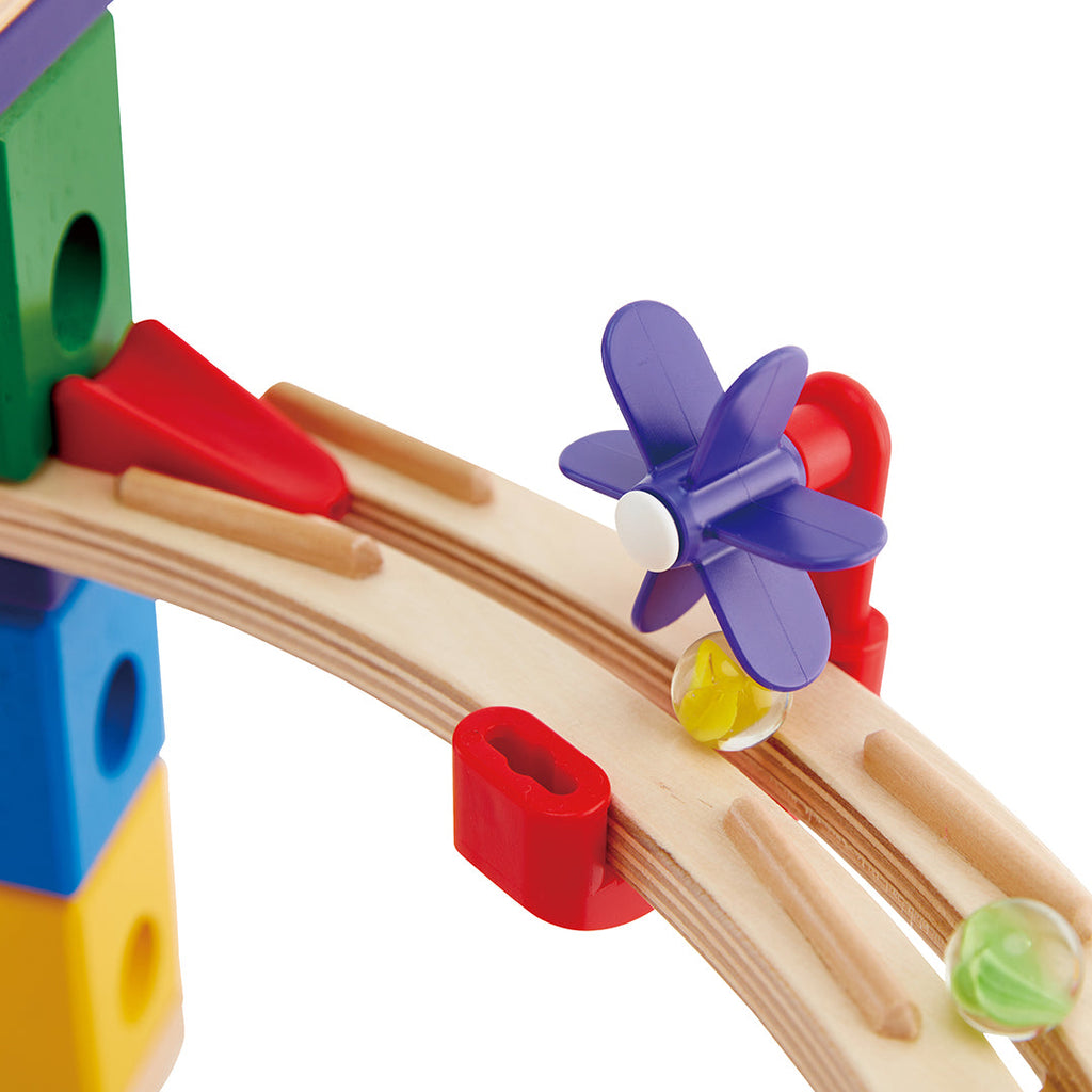 Colourful wooden toy marble run track with a purple flower-shaped piece on a white background