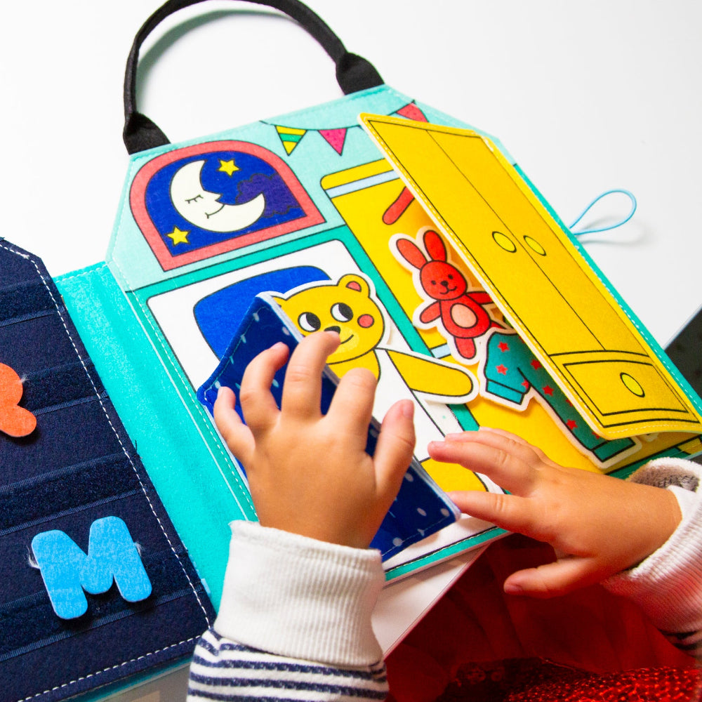 Children's hands interacting with a colorful educational book featuring animals and letters.