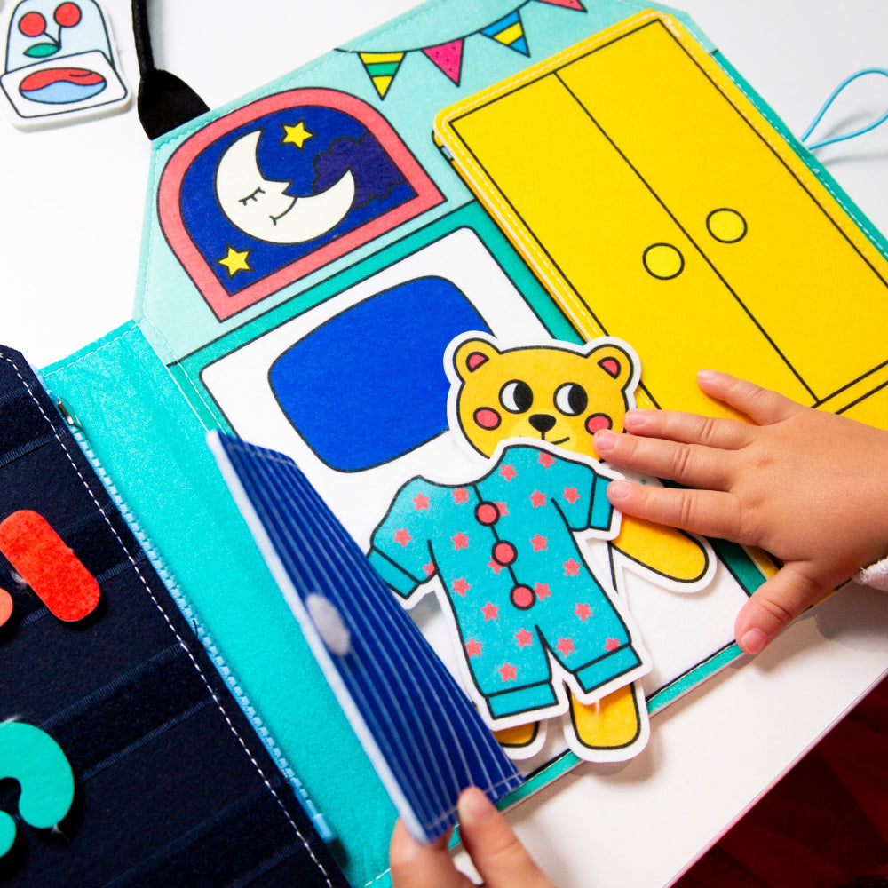 Children's educational toy with colorful felt pieces and a hand interacting with it.