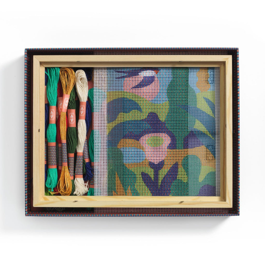 Framed needlepoint with colorful threads on a white background