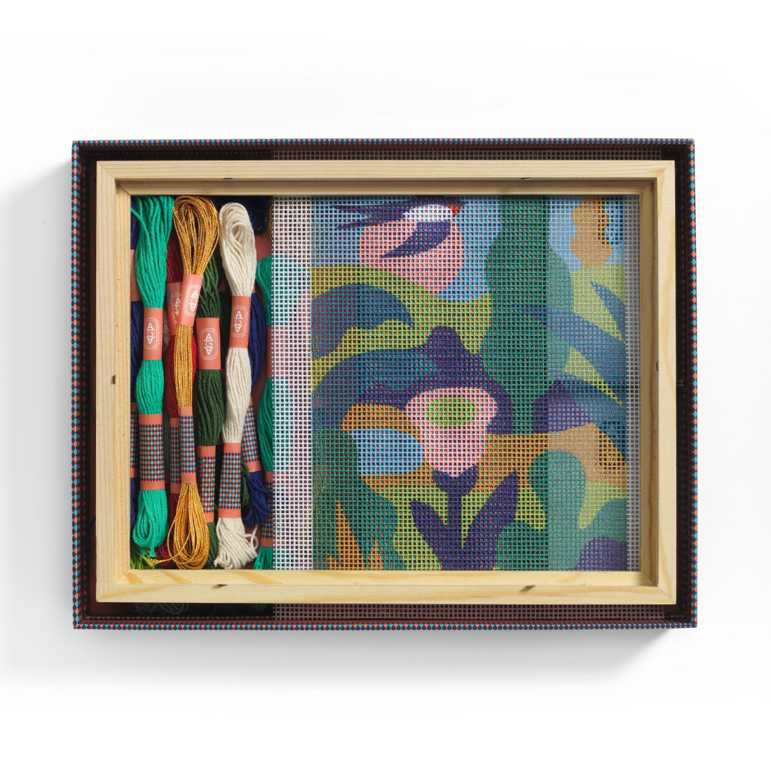 Framed needlepoint with colorful threads on a white background