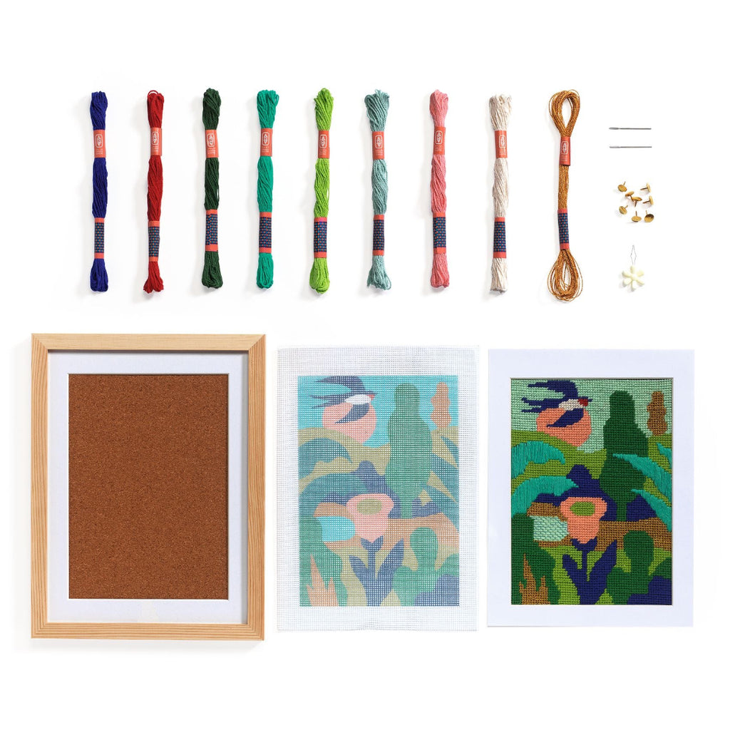 Set of colorful embroidery threads and framed cross-stitch art on a white background