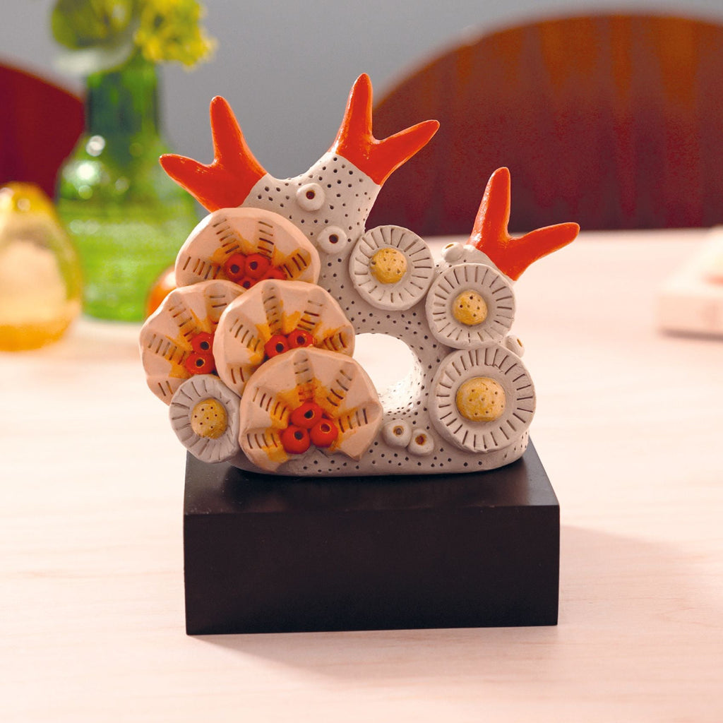 Decorative ceramic piece with orange antlers on a wooden surface