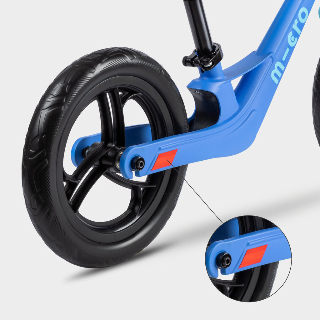 Close-up of the rear wheel on the blue Micro Balance Bike Lite with an inset of the red reflector