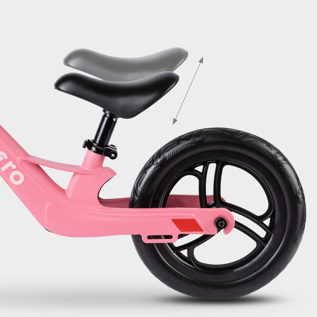 Close-up of the adjustable saddle on the pink Micro Balance Bike Lite, with an arrow showing height adjustment