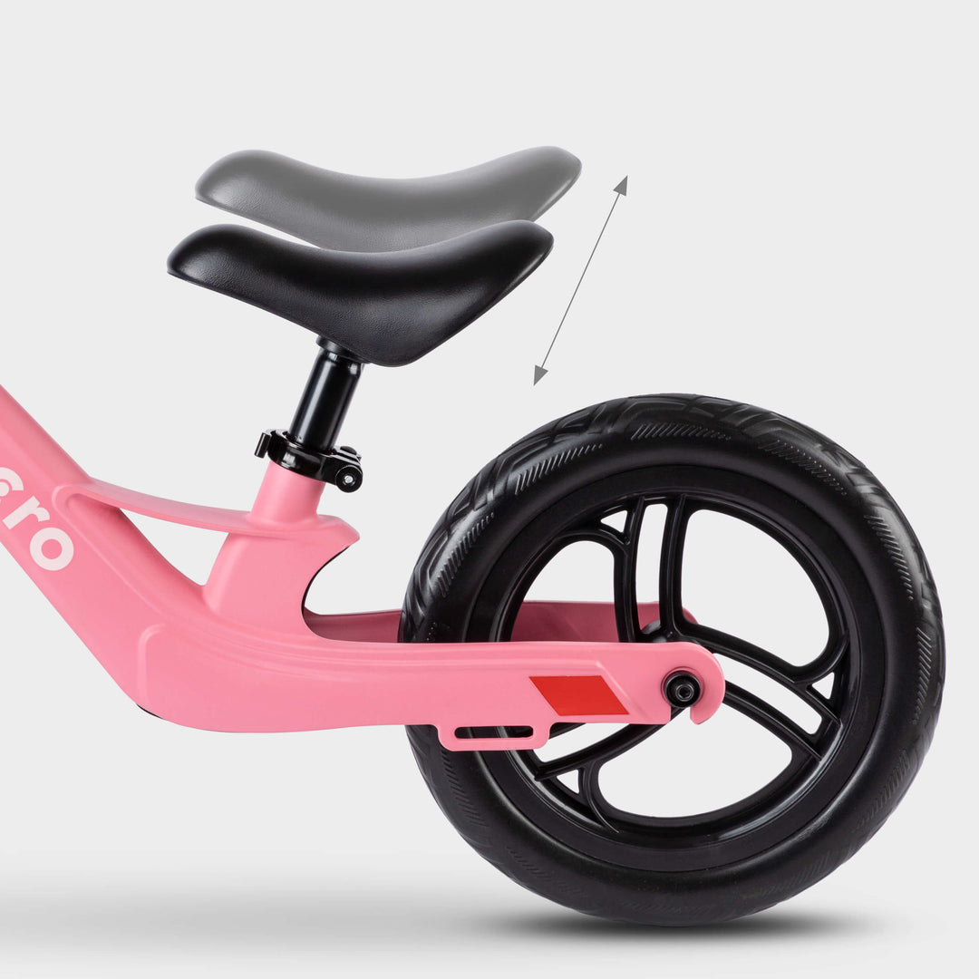 Close-up of the adjustable saddle on the pink Micro Balance Bike Lite, with an arrow showing height adjustment