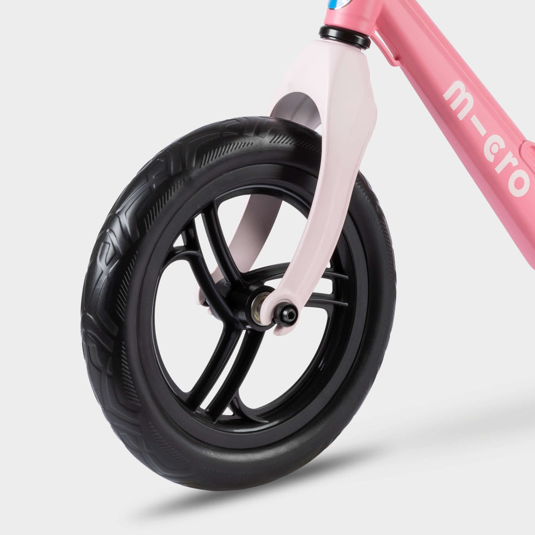 Close-up of the pale pink front fork and black front wheel on the pink Micro Balance Bike Lite
