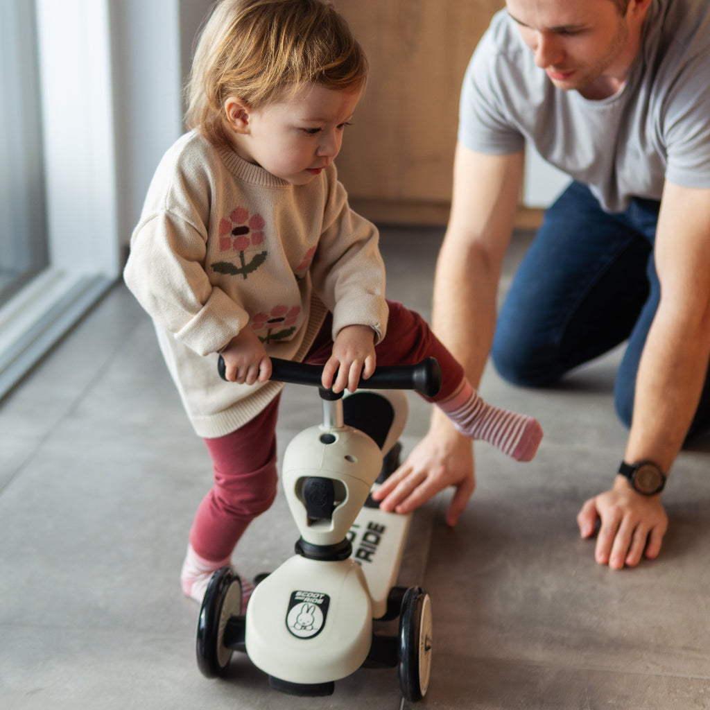 Man and child playing with a toy scooter indoors