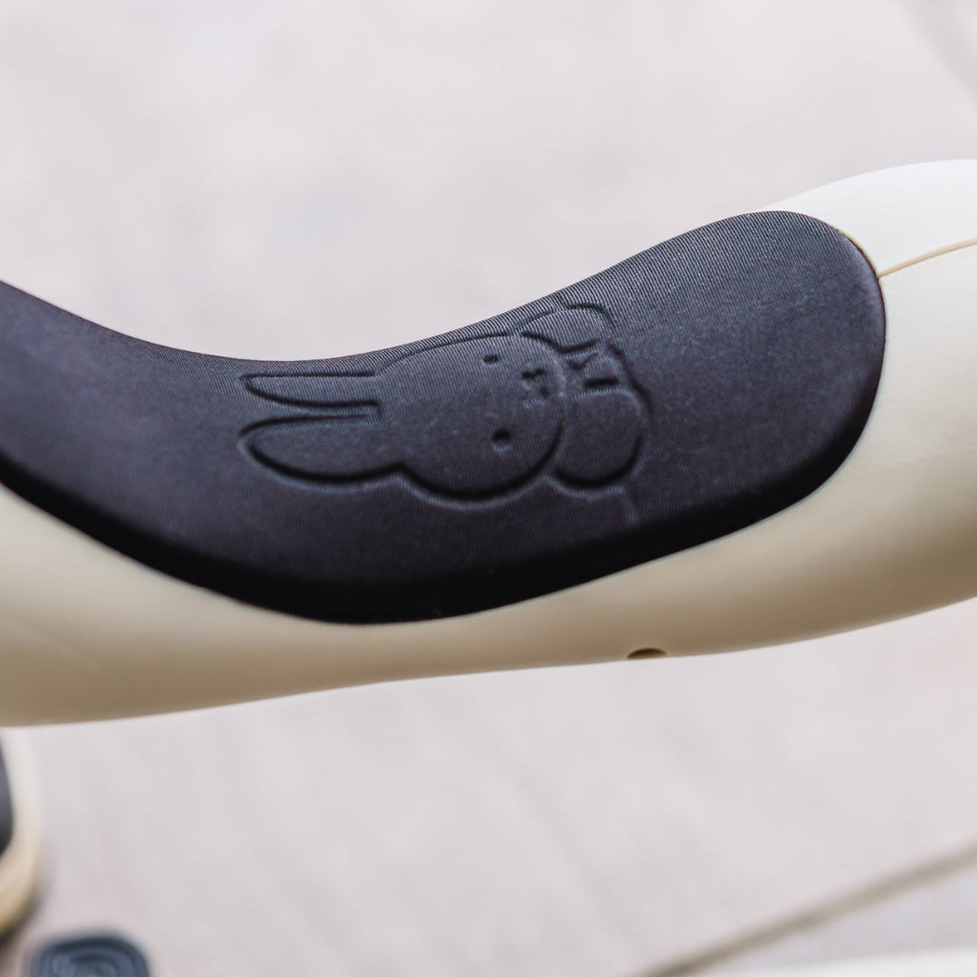 Close-up of a scooter handlebar grip with a black rubberized pad featuring an embossed bunny face, mounted on a cream-colored handlebar. The brand name 'SCOOT RIDE' is partially visible at the bottom.