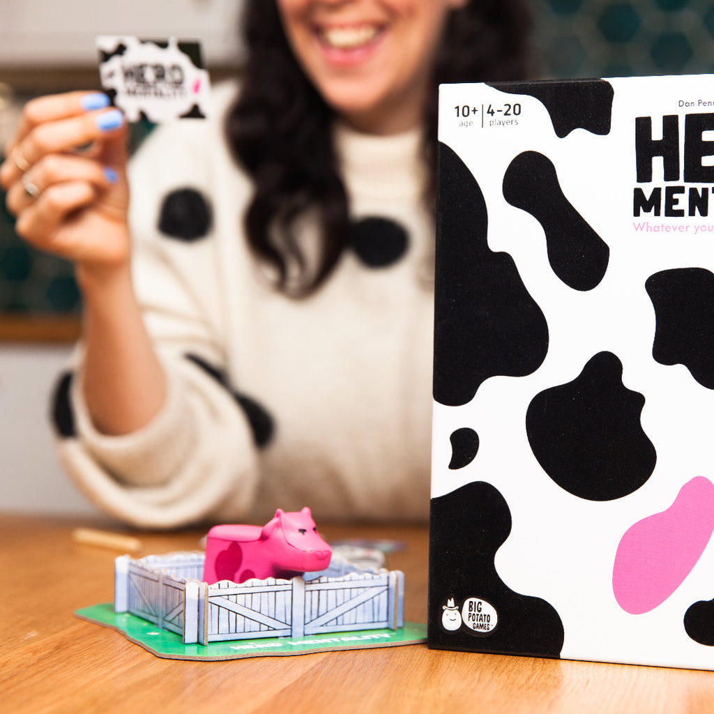 Game box with cow print design and pink pig figure on a wooden surface