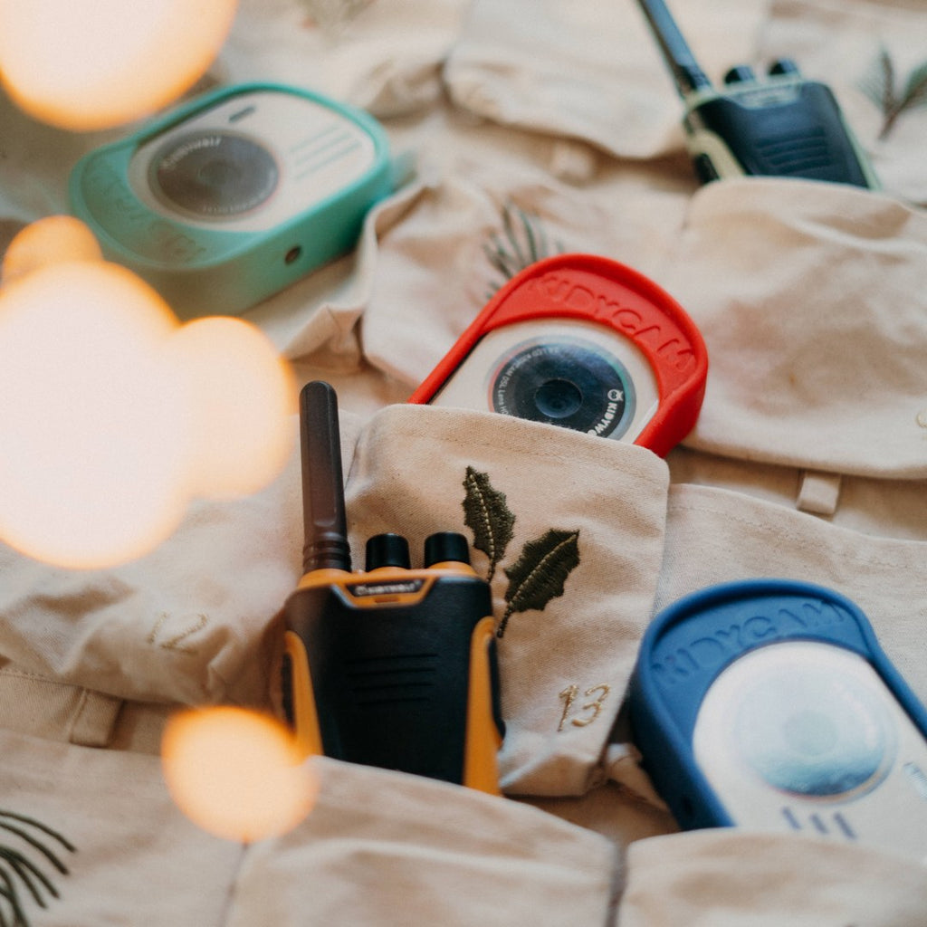Orange KIDYTALK walkie-talkie tucked into a fabric advent calendar pocket next to Kidywolf KIDYCAM cameras