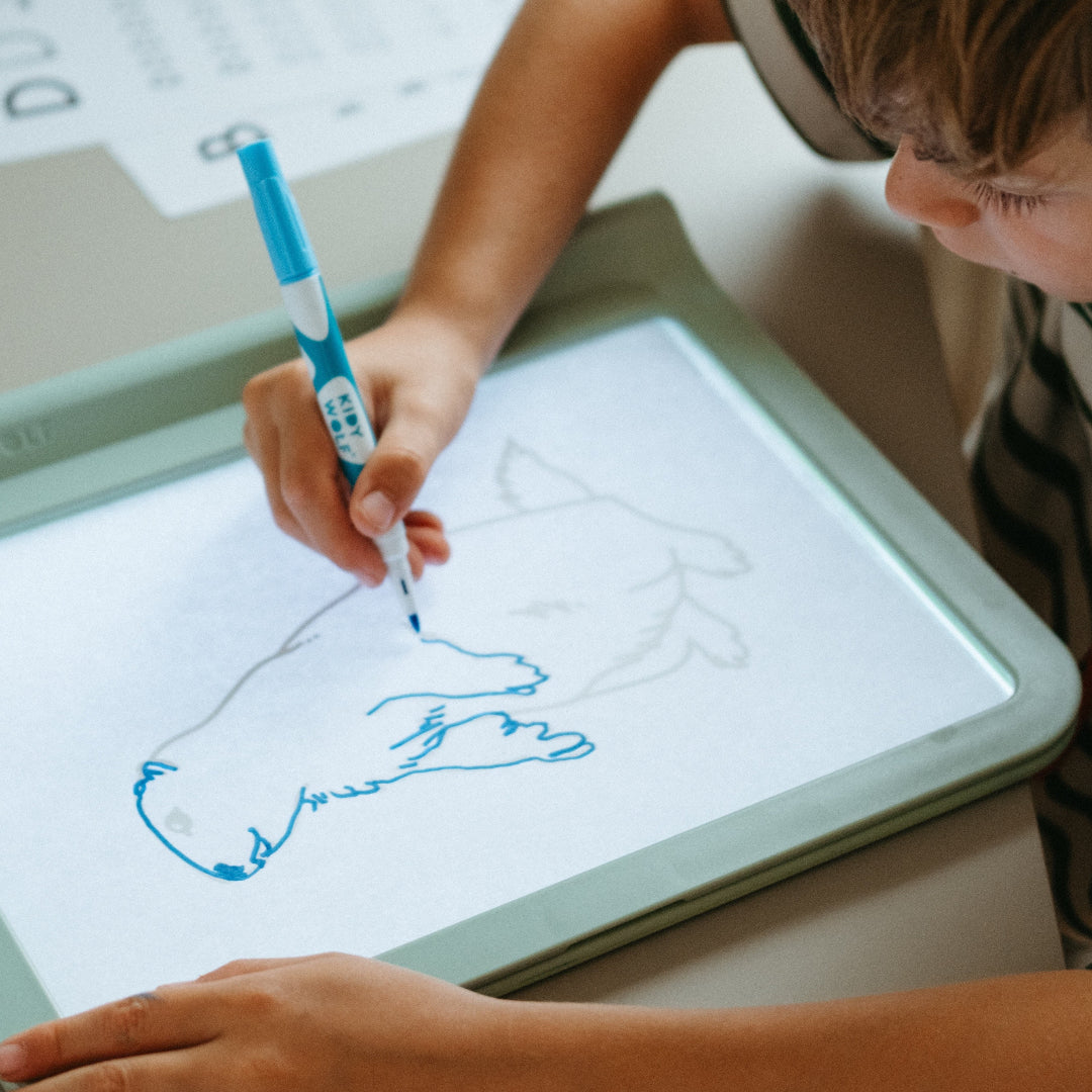 Child drawing on a lightboard with a blue marker