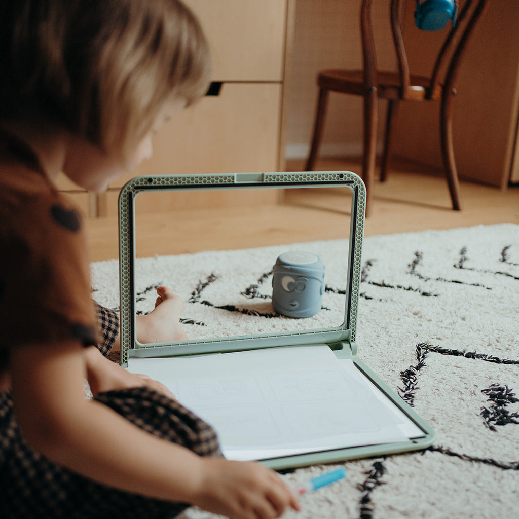 Child sitting on a rug with a tablet drawing.