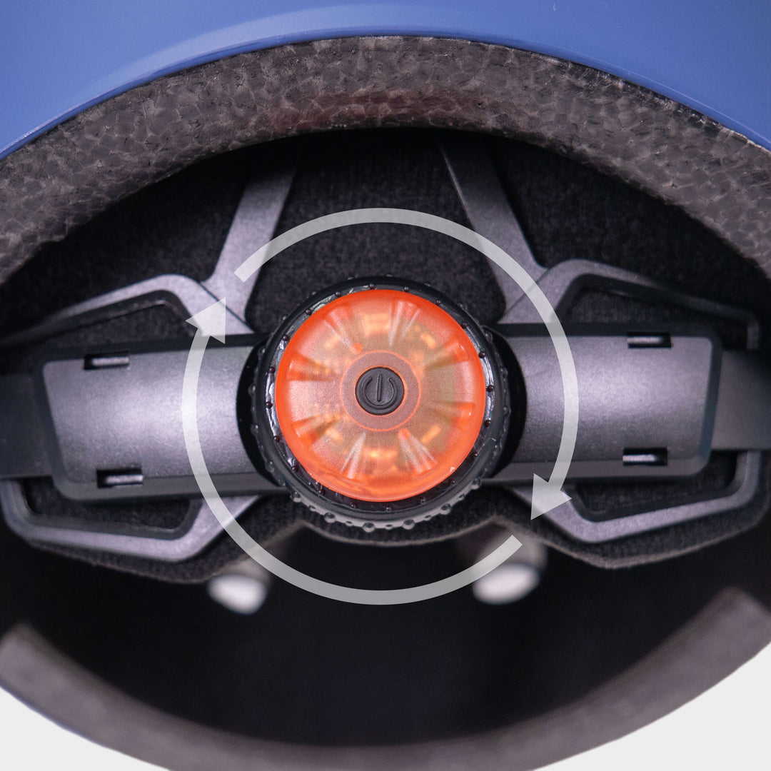 Close-up of the rear dial fit adjuster and light on the navy Micro helmet, with arrows showing it turning