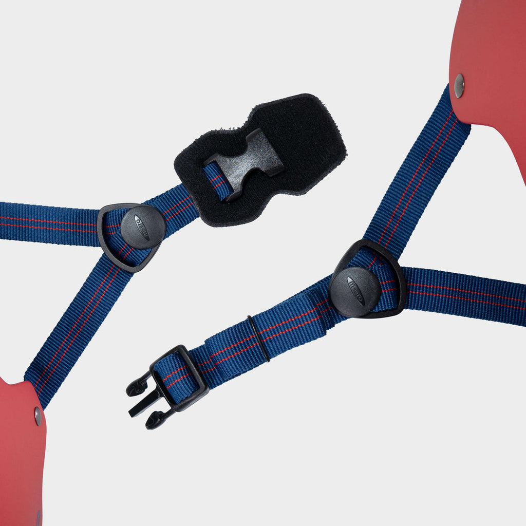 Close-up of the navy adjustable straps and black buckle on the red Micro plain helmet