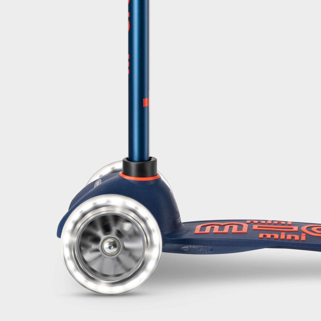 Close-up of the light-up LED front wheels on the navy Mini Micro Deluxe scooter