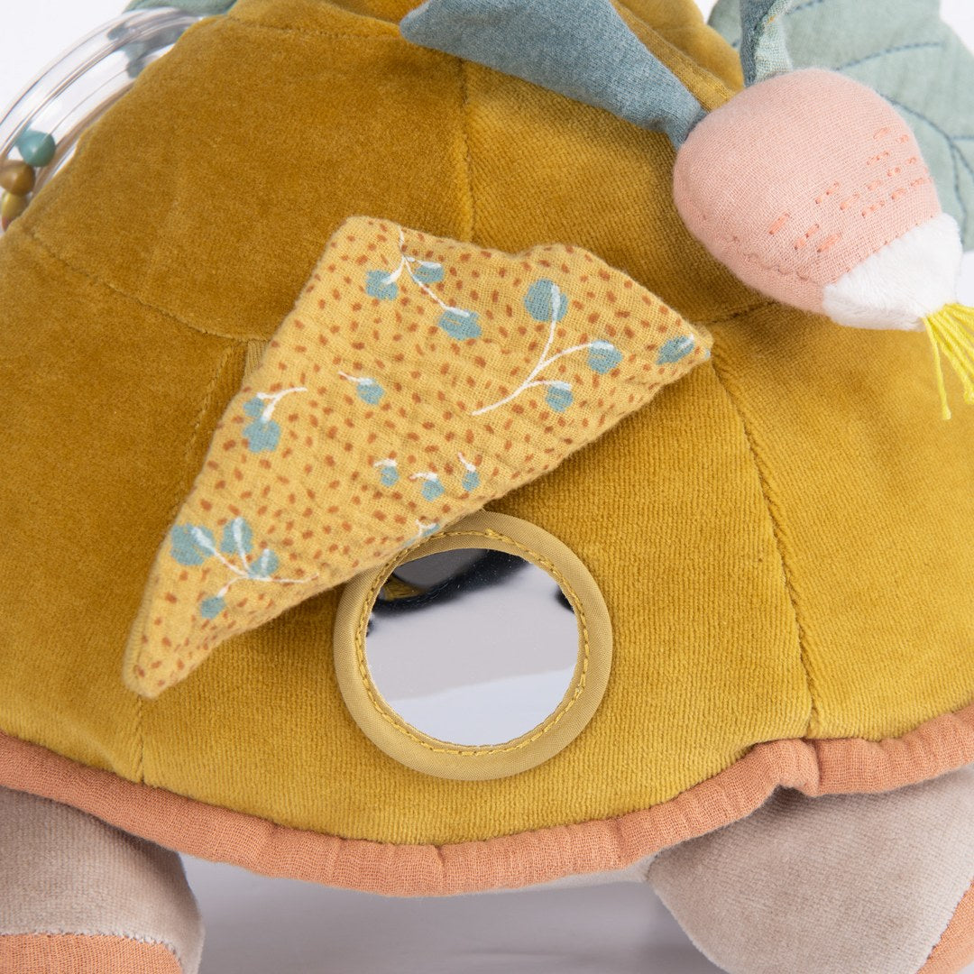 Close-up of the Moulin Roty activity turtle patterned flap lifting to reveal a baby mirror
