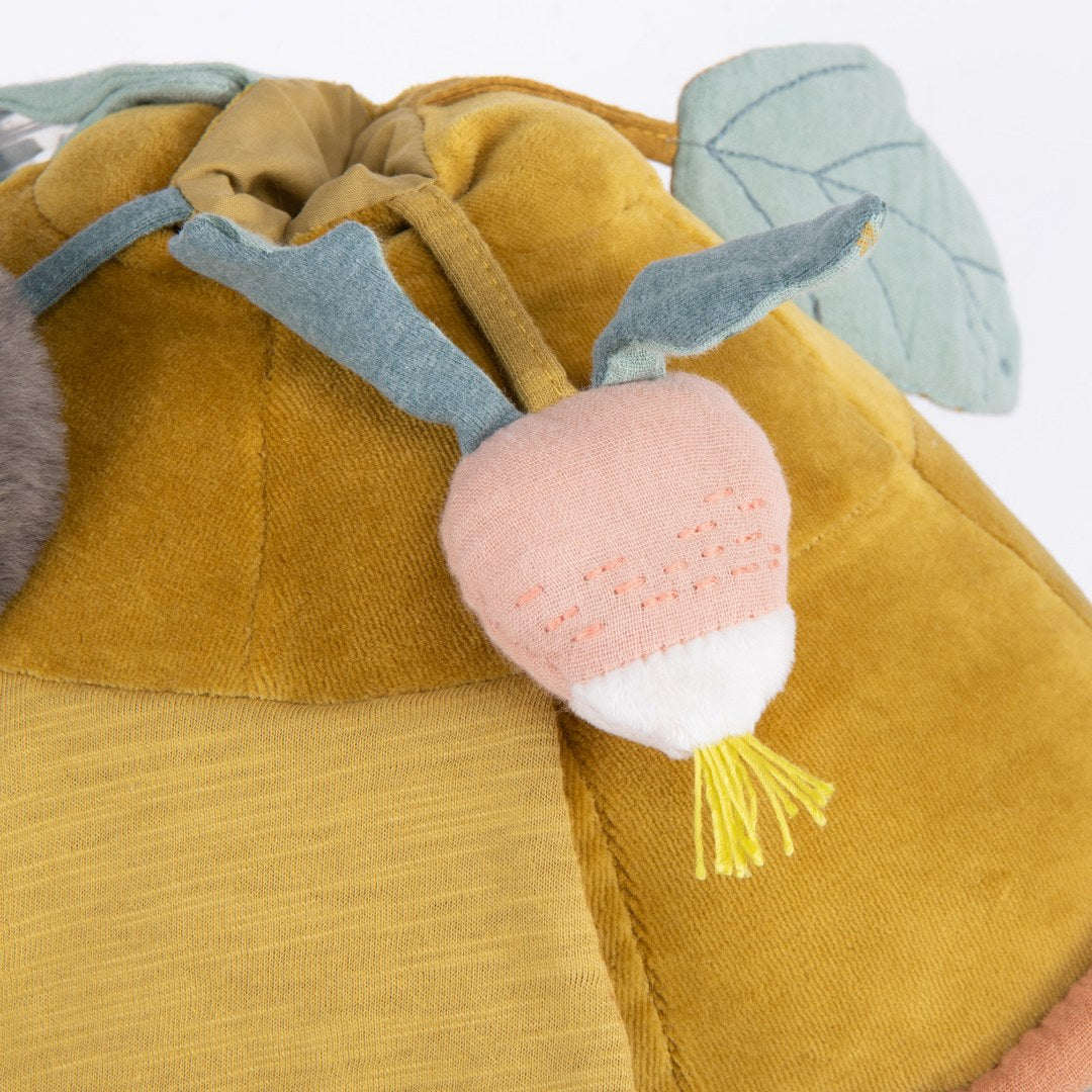 Close-up of the pink radish rattle with ribbon leaves on the Moulin Roty activity turtle