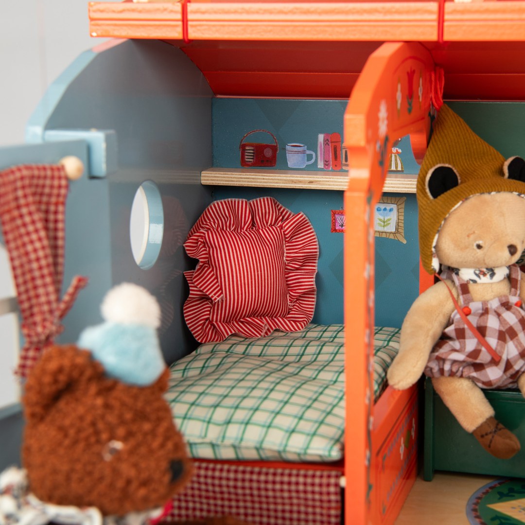 Close-up of the caravan bed with ruffled cushion and checked mattress