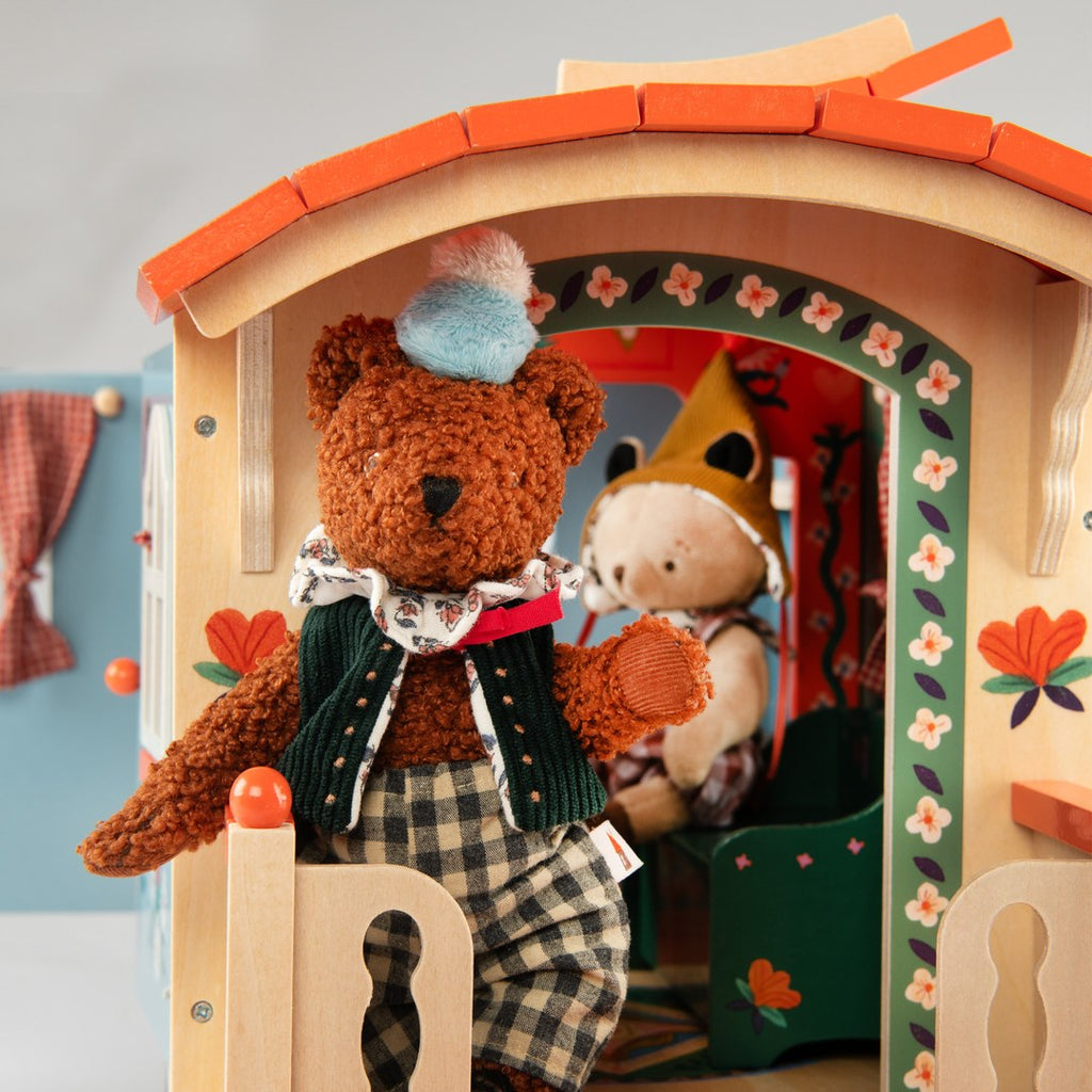 Bear doll in the painted doorway of the Moulin Roty wooden caravan