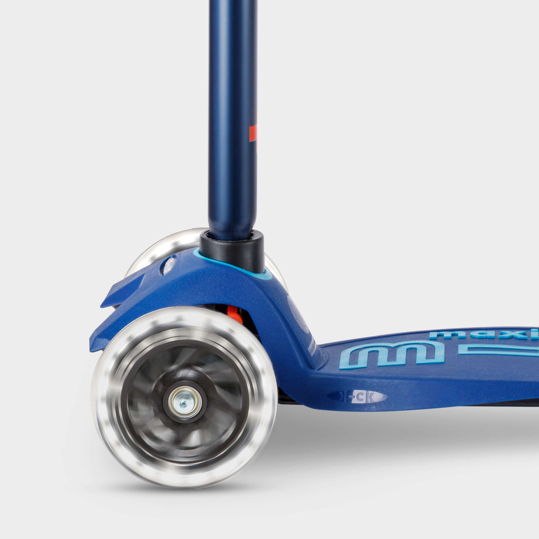 Close-up of the light-up LED front wheels on the navy Maxi Micro Deluxe scooter